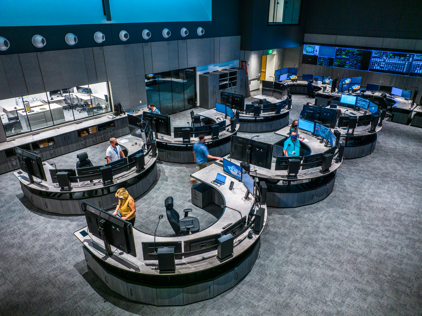 a wide view of six custom consoles with operators working.