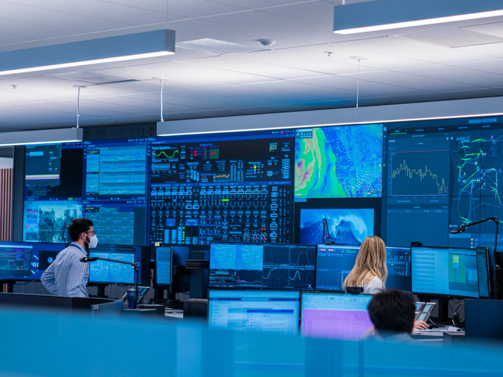 a small group of operators working at stations with a video wall in front of them.