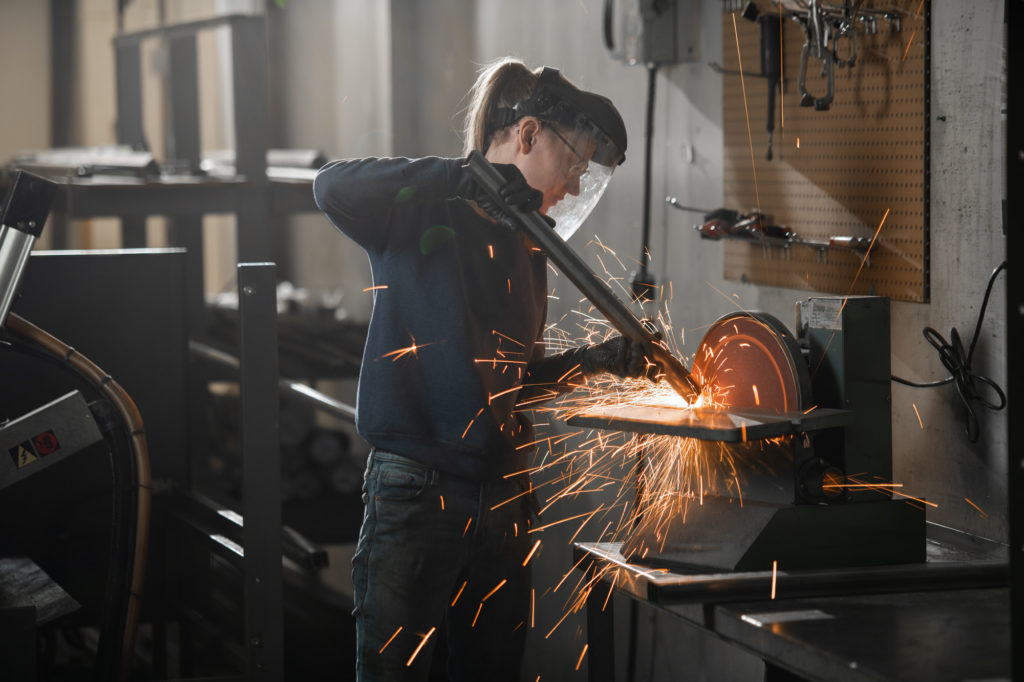 Skilled woman molding steel pipe on a high powered sawblade