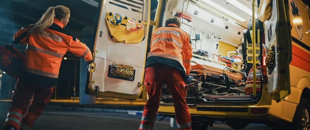 two EMTs rushing to get a patient in the back of an ambulance