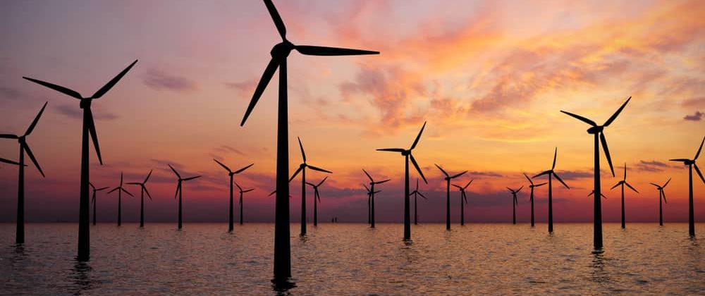 Windmills scattered in water at sunset