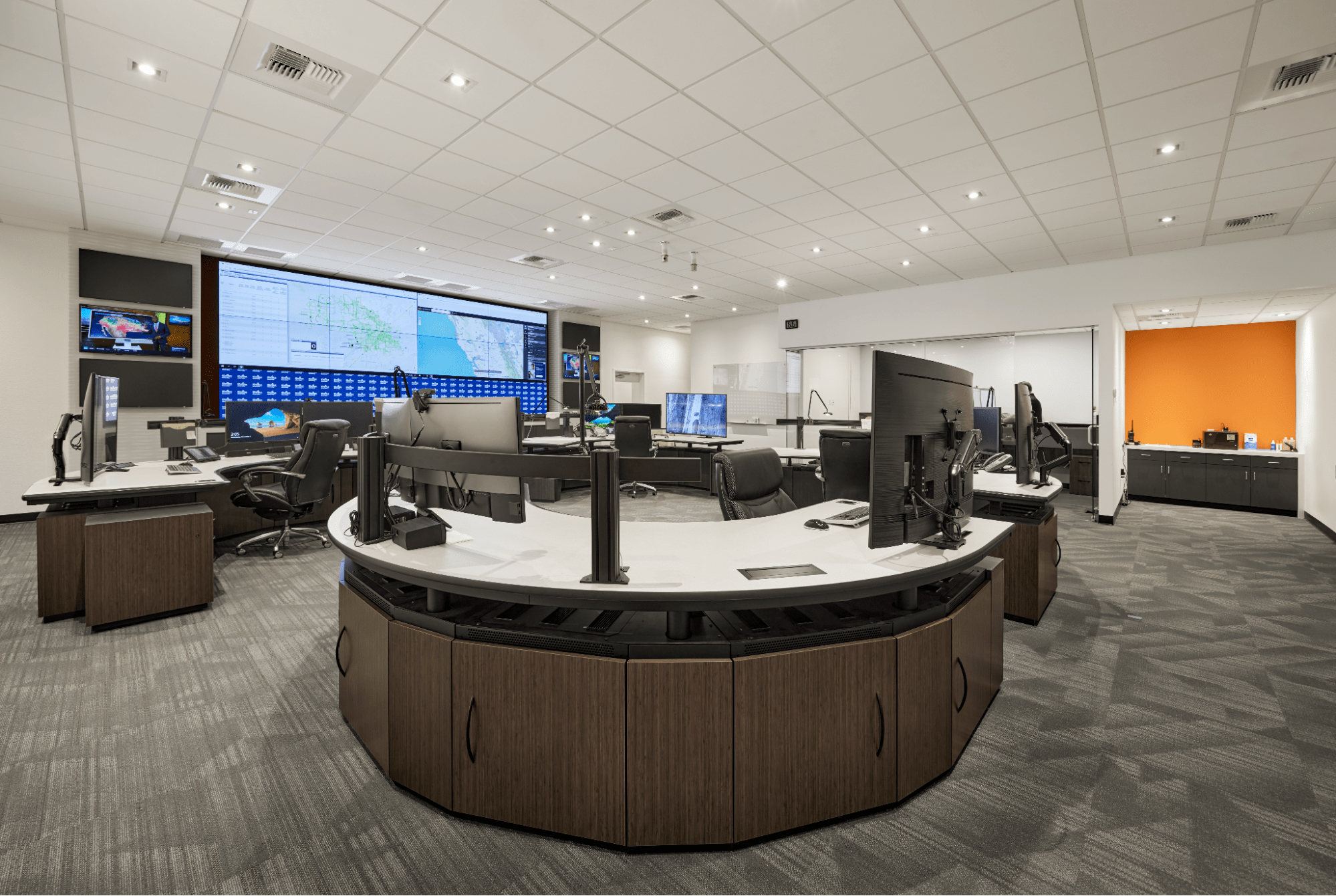 A wide view of a control room with computers and a video wall
