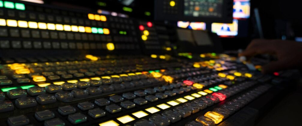 a control room console with screens, buttons, and lights.